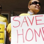 In this Sept. 24, 2010 photo, supporter Marisa Salas, right, holds a sign during a foreclosure and eviction rally at the home of Carlos Moreno in Menlo Park, Calif. Moreno has owned his home since 2006, had his home under foreclosure  since January 2010, and was served eviction notice in July 2010. His case is now pending with the bank. For most Americans at risk of losing their homes, the brutal business of foreclosure goes on. (AP Photo/Paul Sakuma)