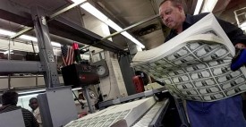 A Bureau of Printing and Engraving employee holds sheets of one dollar bills prior to cutting at a plant in Washington, D.C. (AP/Hillery Smith Garrison)